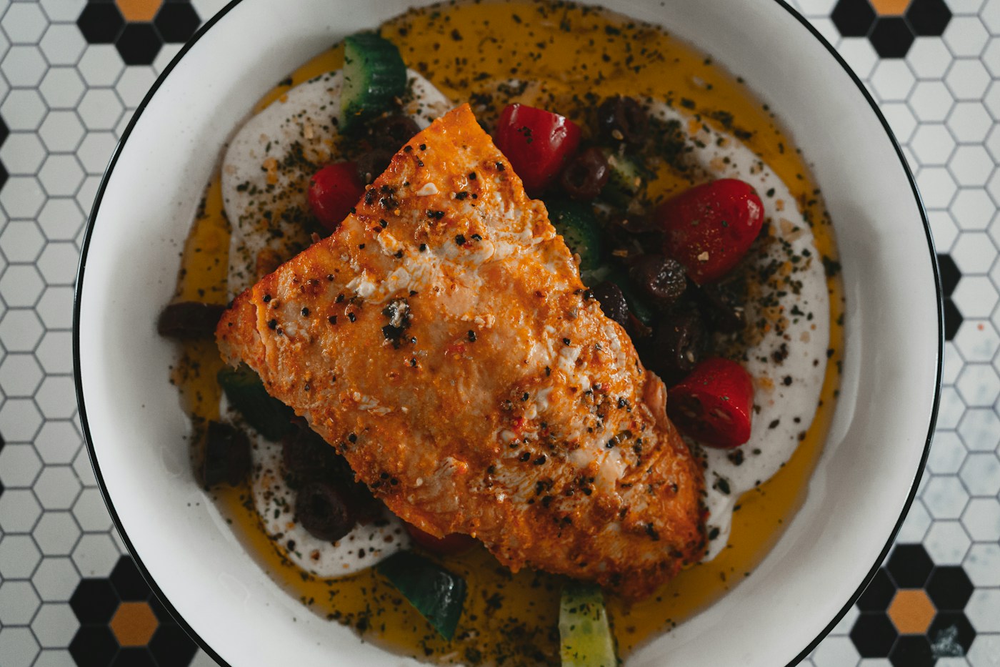 Cooked fish fillet served over white purée with seasoned garden vegetables